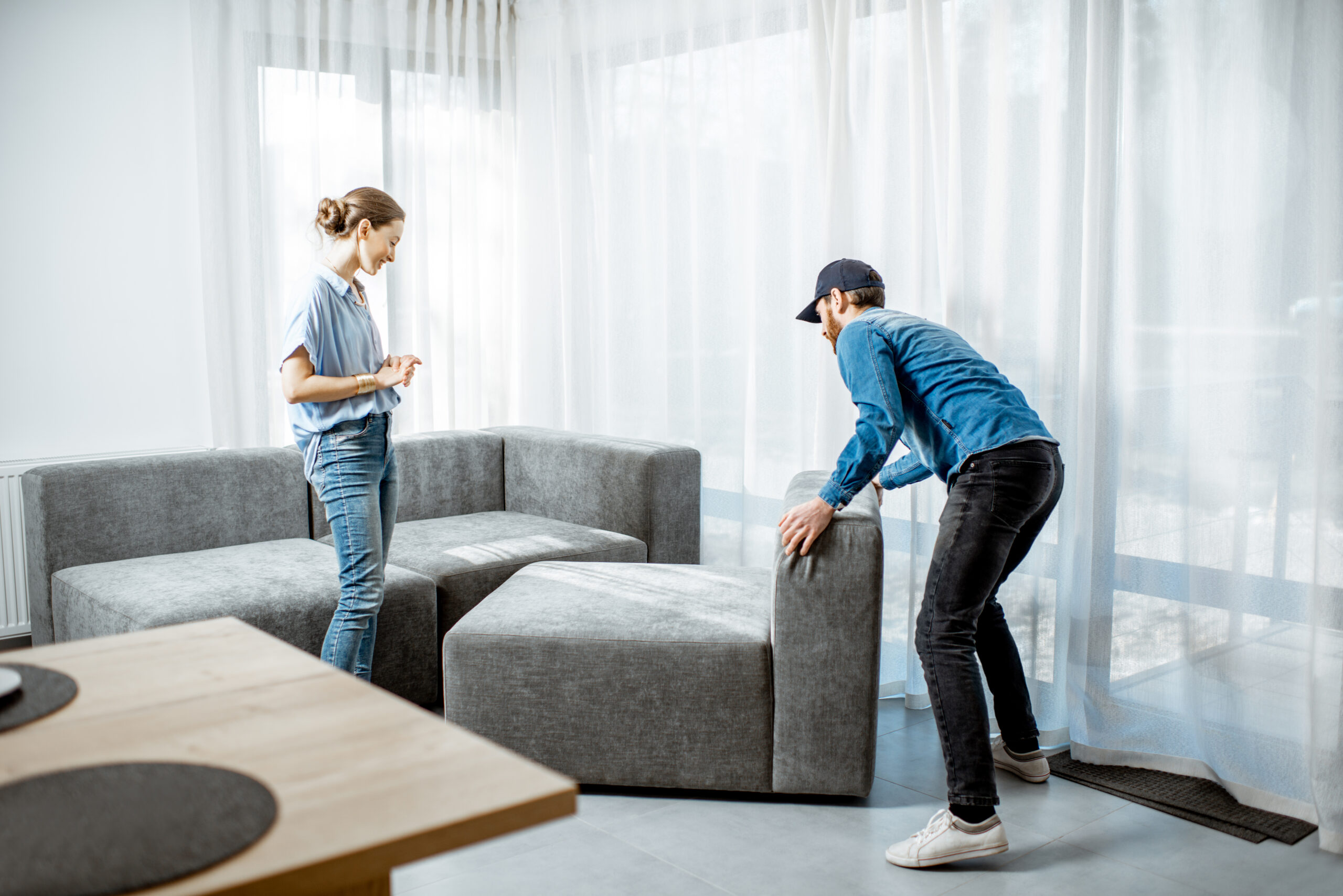 Delivery man mounting new sofa for a young woman client in the modern apartment